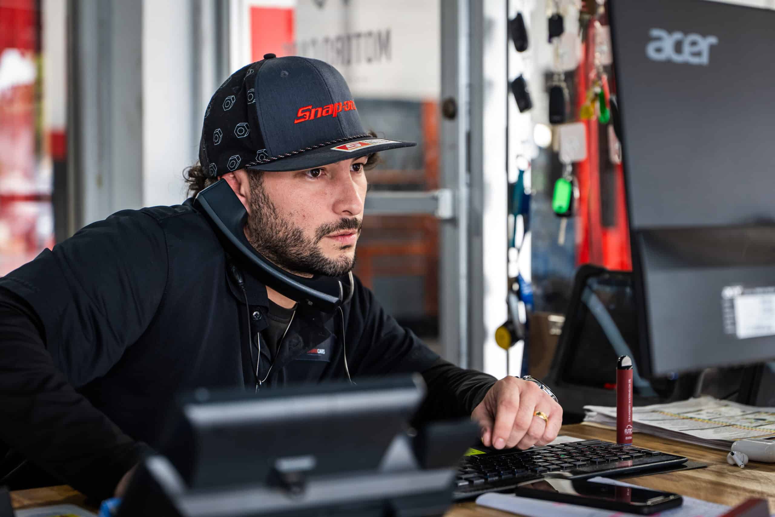 Auto service writer on phone while looking at computer monitor.
